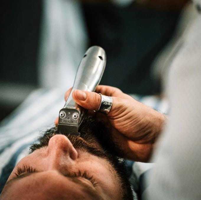 Beard being trimmed with an electric razor by a barber.